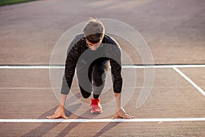 Athlete on starting position at running track. Runner practicing run in stadium racetrack