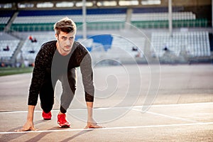 Athlete on starting position at running track. Runner practicing run in stadium racetrack