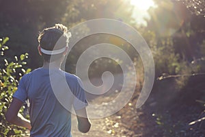 athlete in a sweatband jogging on a sunlit trail photo