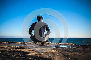 Athlete taking break sitting on rocks with sea horizon