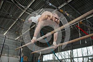 Athlete topless doing exercises on the uneven bars