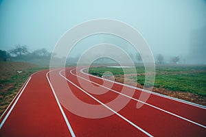 Atletická dráha nebo běžecká dráha s modrým zamlženým pozadím. Bílá editační mezera