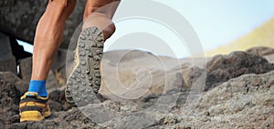 Athlete trail running in the mountains on rocky terrain