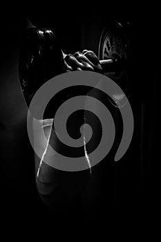 Athlete trains biceps hands with dumbbells in the center of workouts on a black background. training tools in the gym close-up photo
