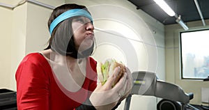 The athlete trains on a bicycle simulator and eats a burger.