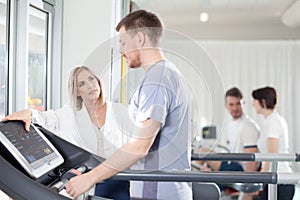 Athlete on a treadmill with physiotherapist doctor photo