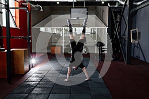 Athlete walking on his hands standing upside down in gym.