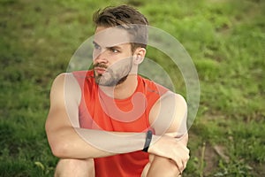 Athlete wear pedometer bracelet on hand. Athletic man relax on green grass. Checking workout results. Technologies make