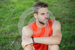 Athlete wear pedometer bracelet on hand. Athletic man relax on green grass. Checking workout results. Technologies make