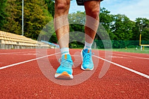 Athlete Wearing Bright Blue Running Shoes on Red Stadium Track During Training