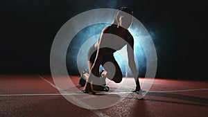 Athlete woman in black shorts and a t-shirt in sneakers are in the running pads on the track of the sports complex and