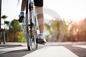 Athlete woman cyclist legs riding Mountain Bike on the road in the morning