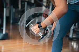 Athlete woman lifting dumbbell, doing exercise at gym
