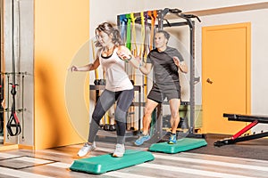Athlete woman and man doing lateral step up jumps in health club