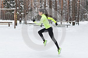 Athlete woman runner running in cold snowing weather. Cardio street training marathon jogging.