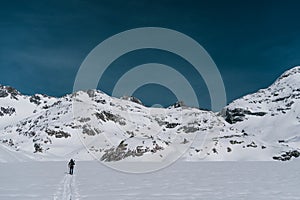 Athletes doing backcountry ski with a landscape of snowy mountains on a sunny day.