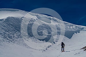 Athletes doing backcountry ski with a landscape of snowy mountains on a sunny day.