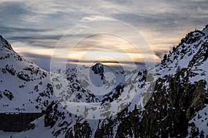 Athletes doing backcountry ski with a landscape of snowy mountains on a sunny day.