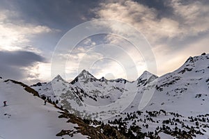 Athletes doing backcountry ski with a landscape of snowy mountains on a sunny day.