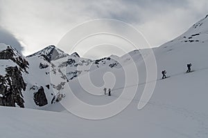 Athletes doing backcountry ski with a landscape of snowy mountains on a sunny day.