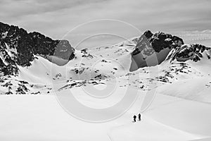 Athletes doing backcountry ski with a landscape of snowy mountains on a sunny day. Black and white