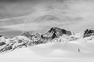 Athletes doing backcountry ski with a landscape of snowy mountains on a sunny day. Black and white