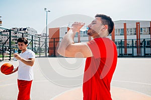 Athletes drinking water and having a break after a long exhausting basketball game