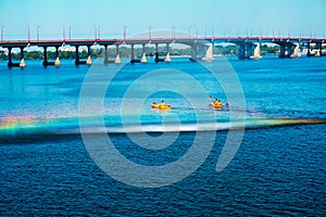 Athletes in kayaks in training near the river fountain in a rainbow of splashes