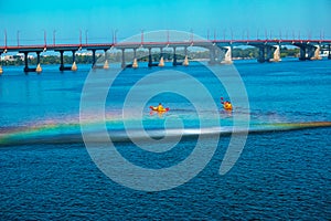 Athletes in kayaks in training near the river fountain in a rainbow of splashes