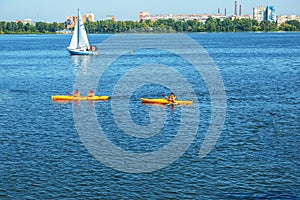 Athletes in kayaks in training near the river fountain in a rainbow of splashes