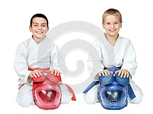 Athletes in kimono sitting in a ritual pose karate with helmets isolated