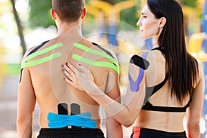 Athletes with kinesiological taping posing at sports ground.