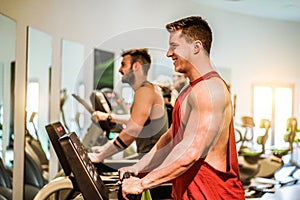 Athletes training on tapis roulant - Fitness men running on gym machine - Wellness and body building concept - Soft focus on blond