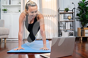 Athletic and active senior woman doing online plank climbing at home. Clout