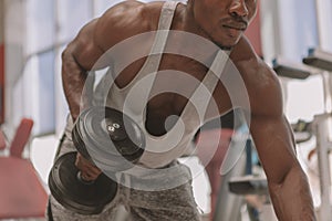 Athletic African man working out with dumbbells at the gym