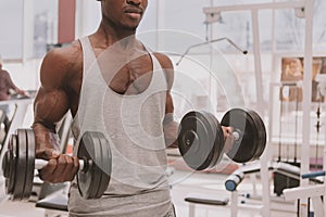 Athletic African man working out with dumbbells at the gym