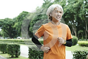 Athletic asian senior woman running outdoor jogging in park.