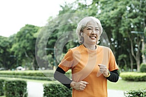 Athletic asian senior woman running outdoor jogging in park.