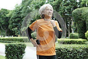 Athletic asian senior woman running outdoor jogging in park.