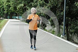 Athletic asian senior woman running outdoor jogging in park.