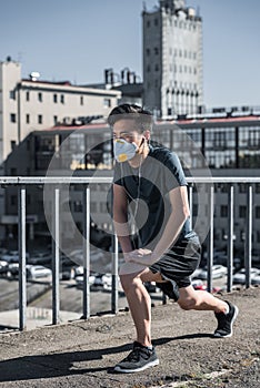 athletic asian teenager stretching in protective mask on bridge air