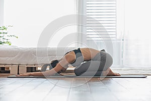 Athletic Asian woman practice yoga Child`s pose to meditation in bedroom