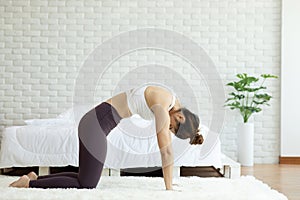 Athletic Asian woman practice yoga Cow pose to meditation in bedroom after wake up