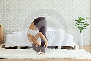 Athletic Asian woman practice yoga Spread foot stretching pose or Prasarita Padottanasana pose