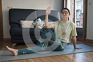 Athletic asian woman in sportswear doing fitness stretching exercises at home.