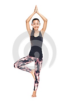 Athletic Asian woman standing in yoga pose tree Vrikshasana
