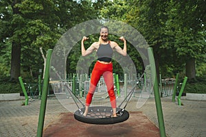 Athletic beautiful middle-aged woman in black and red fitness clothes posing joyfully on the sports ground