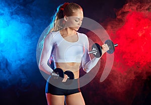 Athletic beautiful young woman doing fitness workout with dumbbells