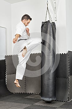 Athletic black belt karate giving a forceful knee kick during a