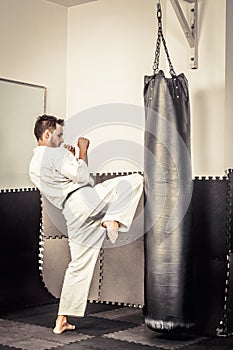 Athletic black belt karate giving a forceful knee kick during a